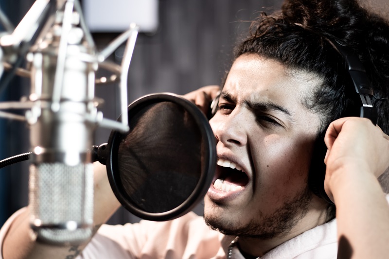 El cantautor Braulio Jacobo canta frente a un micrófono en un estudio de grabación