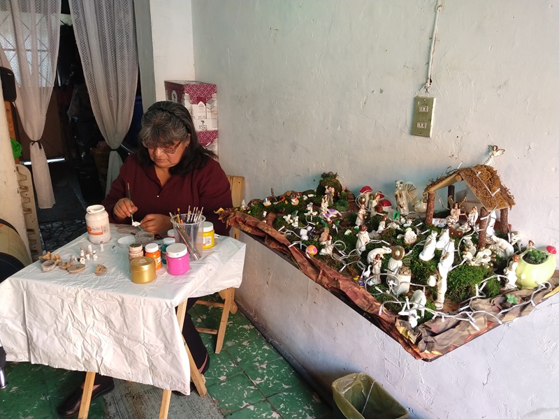 La artesana Lucía Galán Ríos pinta piezas de los nacimientos navideños que elabora con barro. 