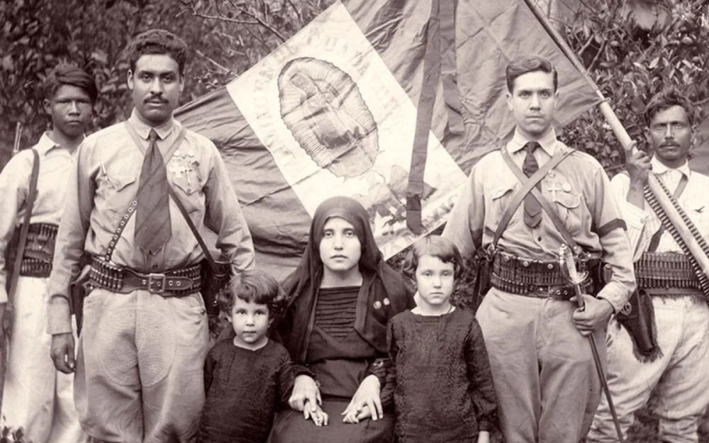 Cuatro hombres, una mujer y dos niñas se muestran uniformados y con una bandera de México con la imagen de la Virgen de Guadalupe. Es una estampa de quienes militaban en la Guerra Cristera, que tuvo su auge en la región Altos de Jalisco