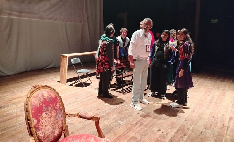 Modesto Hernández y su grupo Teatro de la Ciénega en el escenario de un teatro durante un montaje.